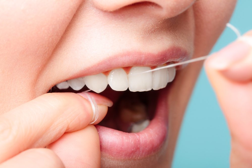 Close up of woman flossing her healthy white teeth